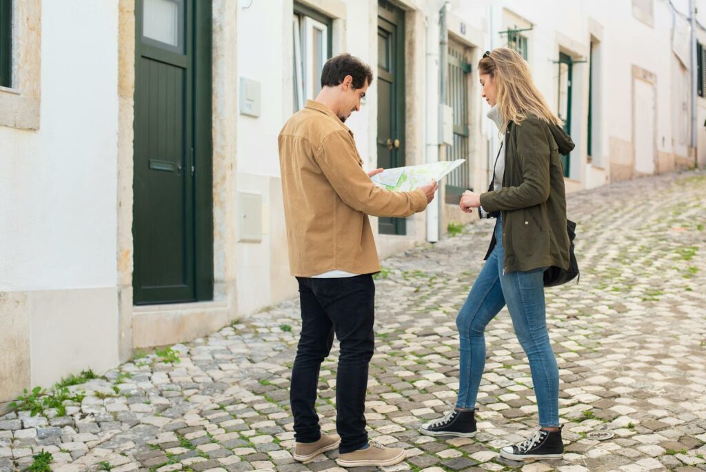 A young couple consults a map on a cobbled street, planning their travel adventure together.